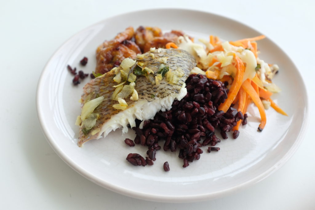 Poisson grillé aux légumes croquants servi avec du riz noir